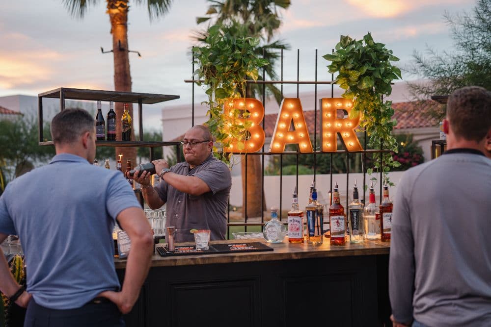 Bartender mixing a drink at the outdoor bar at sunset