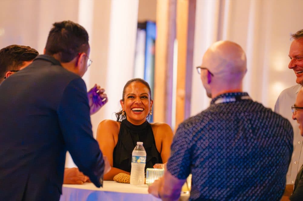 Attendee laughing at a cocktail table during the welcome party