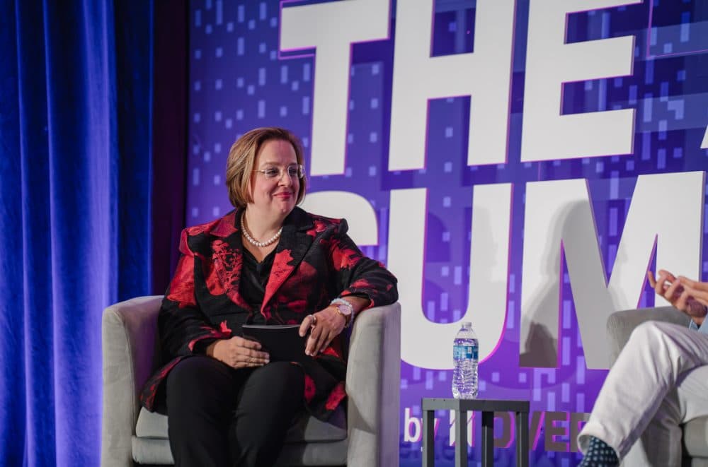 Panelist seated on stage smiling at a fellow speaker