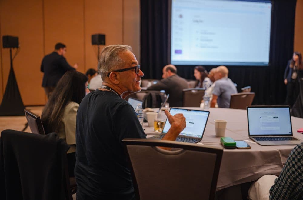 Attendee at a round table with a laptop in front of the main screen