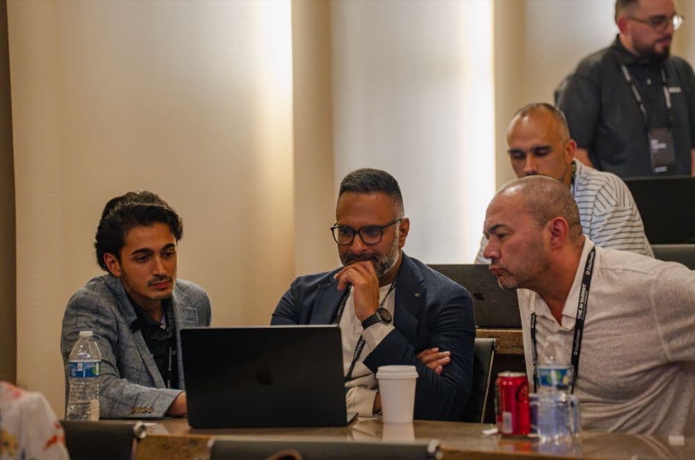 Three attendees looking at a laptop together