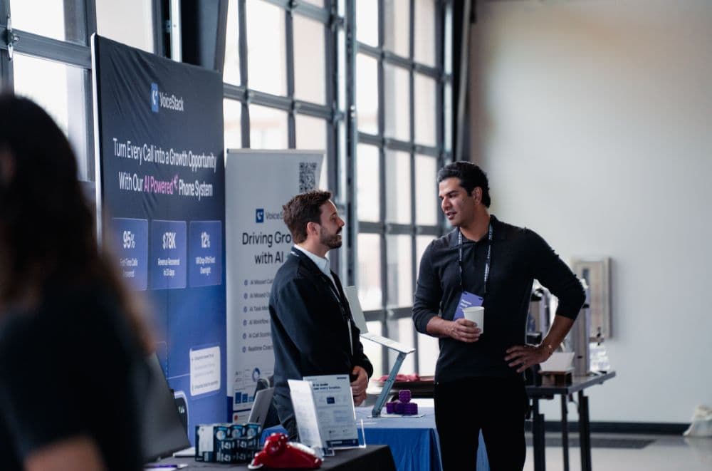 Two attendees chatting at sponsor booths in the pavilion